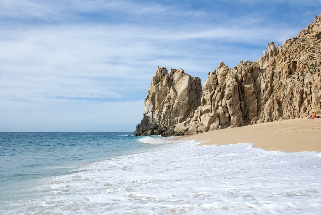 a beach with a large rock formation in the background