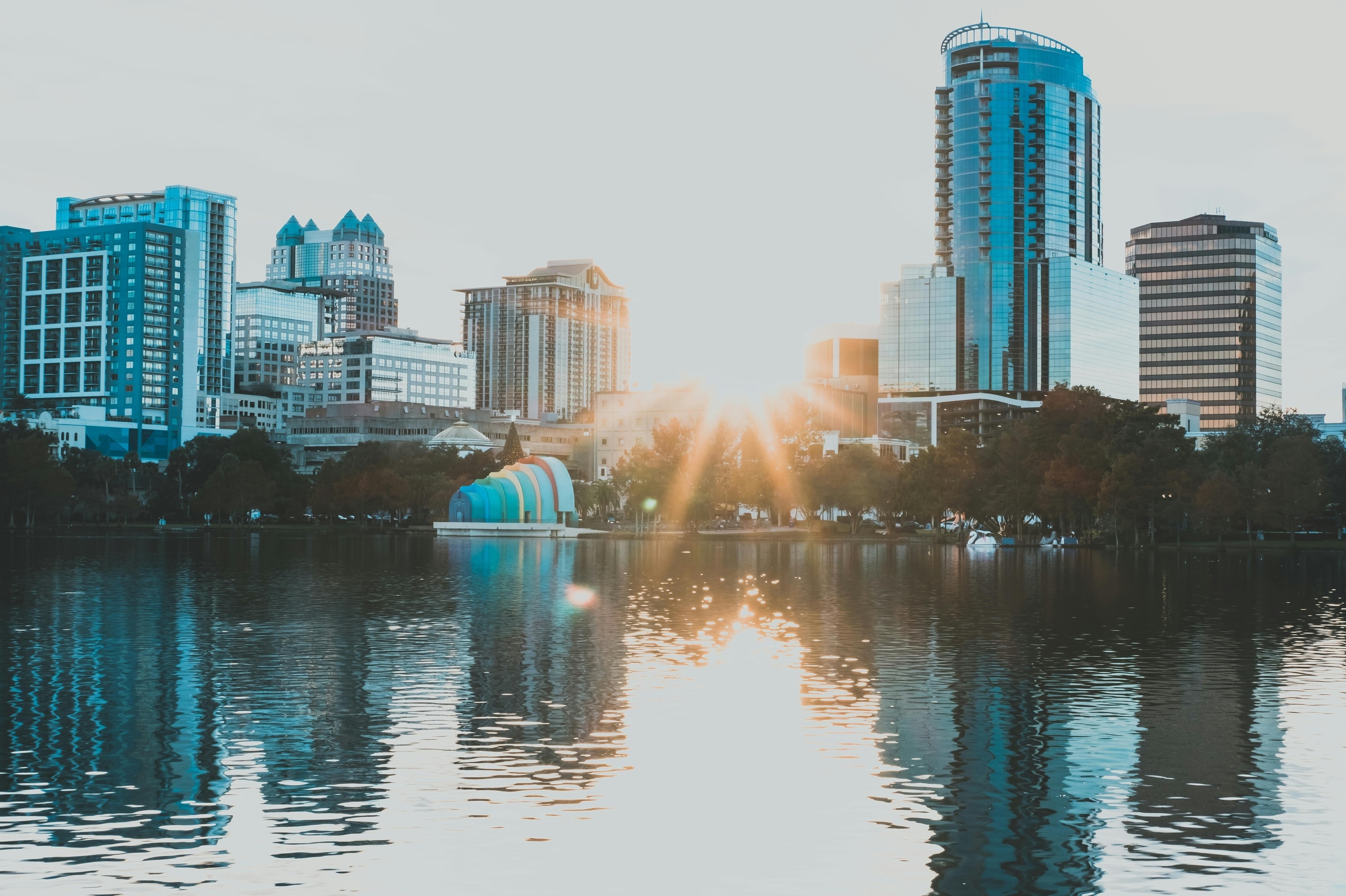 a city skyline with the sun shining through the buildings