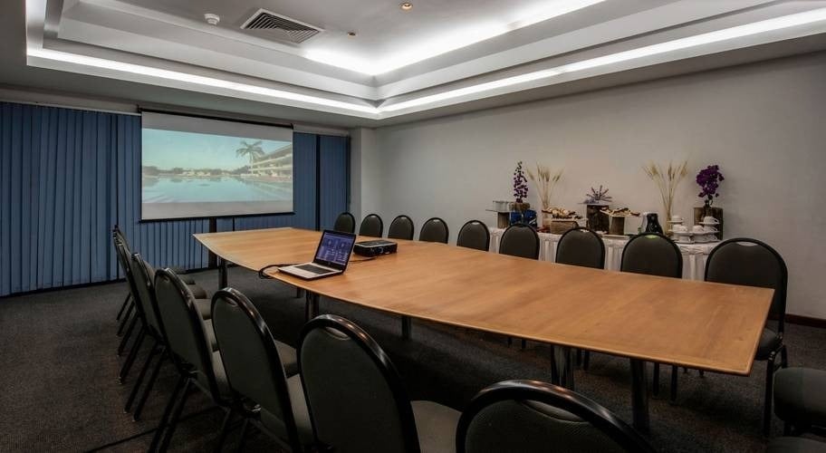 A sala de eventos Guelaguetza com uma grande mesa, poltronas e TV no Park Royal Beach Huatulco