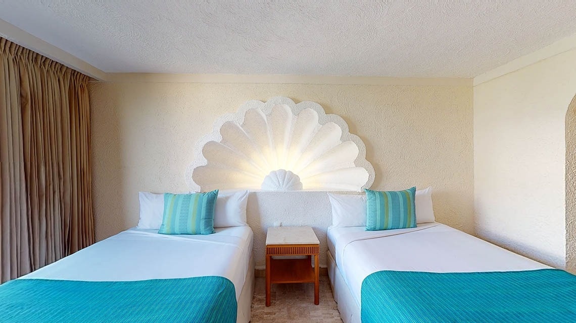 Quarto com duas camas e mesa de cabeceira no Park Royal Beach Acapulco Hotel