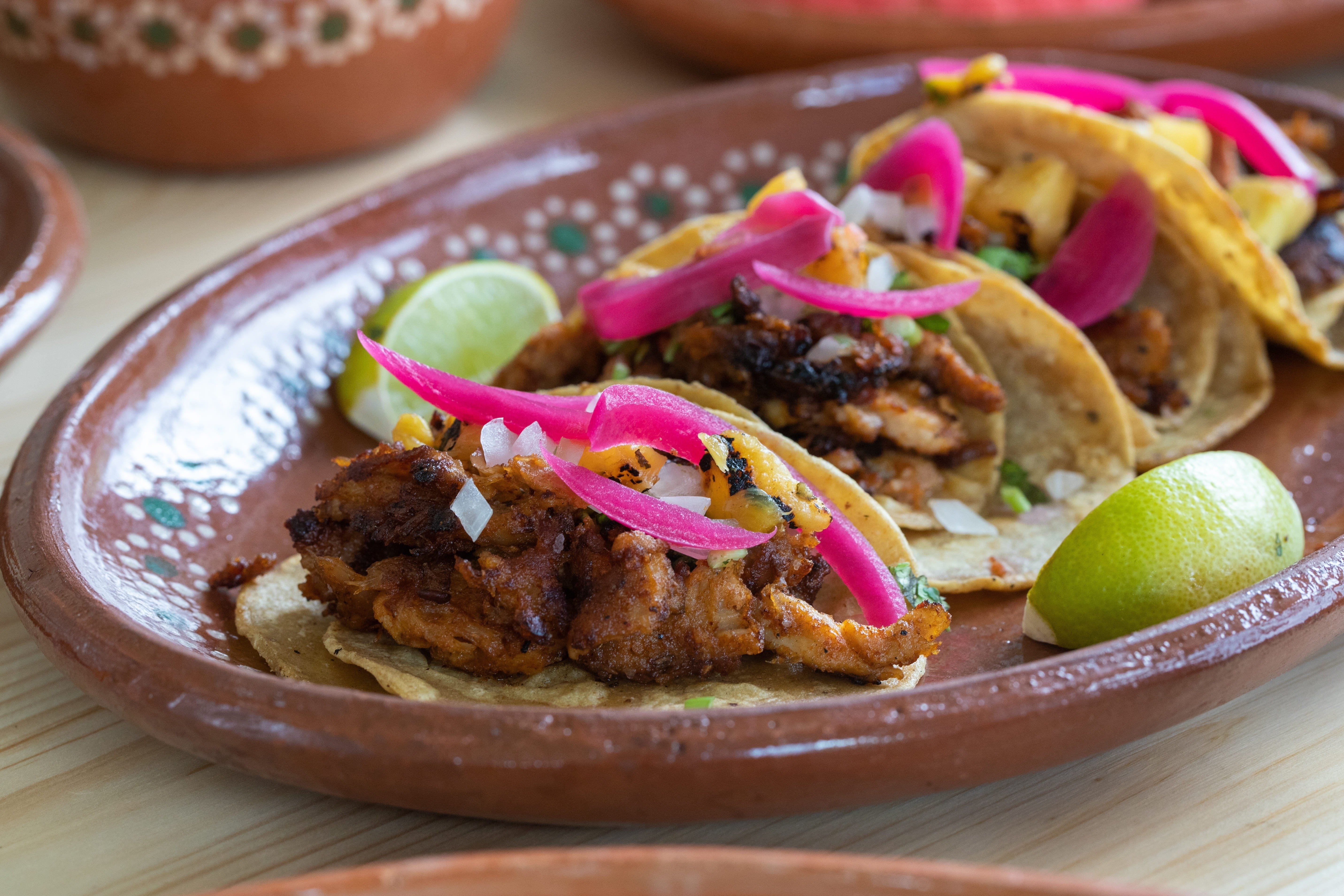 un plato de tacos con cebollas rojas y limón