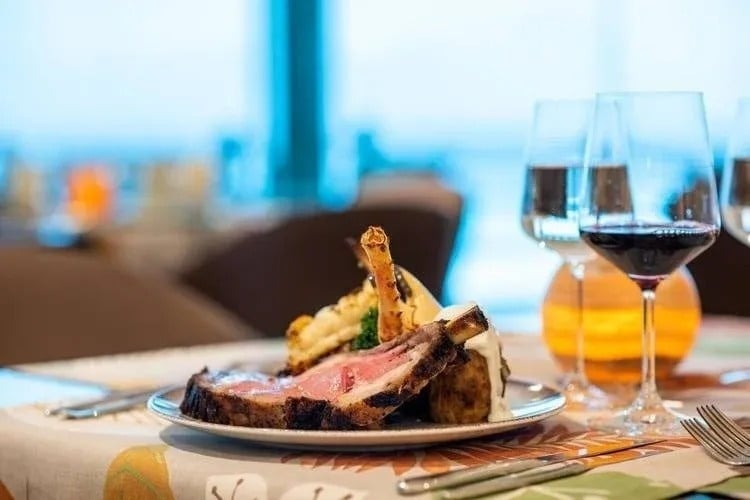 um prato de carne e batatas em uma mesa com dois copos de vinho .