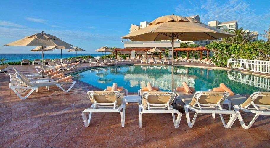 Hamacas con toallas enrollas en una piscina con vistas al mar, Beach Cancún en México