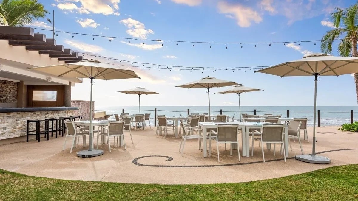 a patio with tables and chairs and umbrellas overlooking the ocean