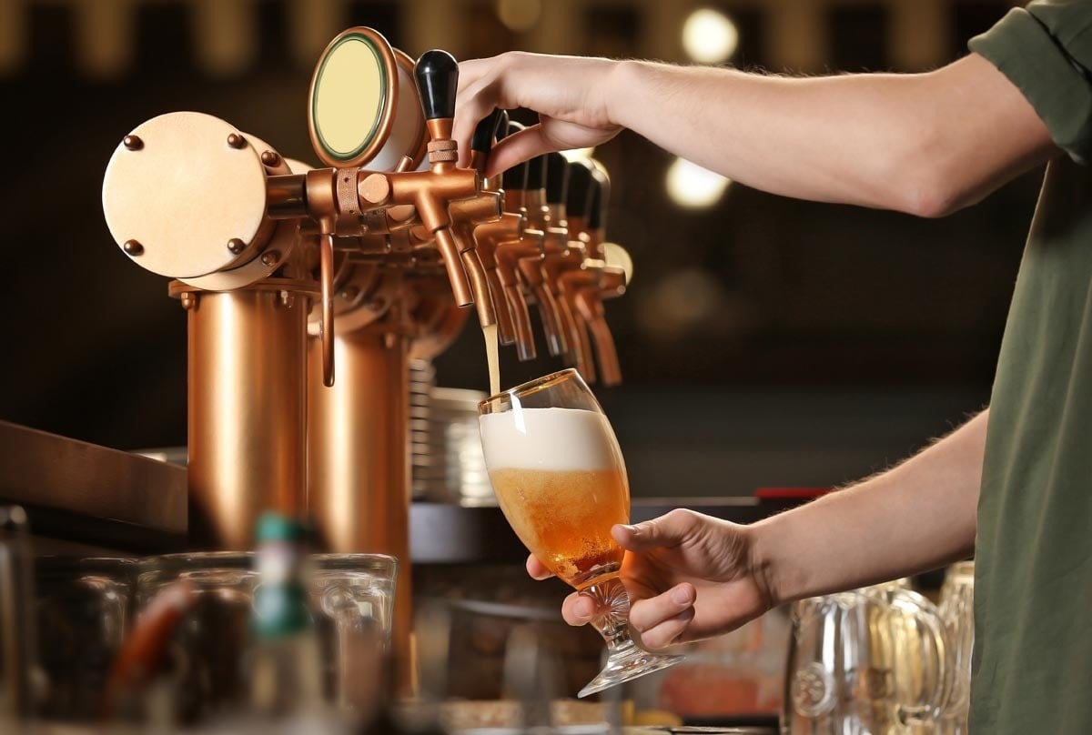 un hombre está vertiendo cerveza en un vaso en un bar
