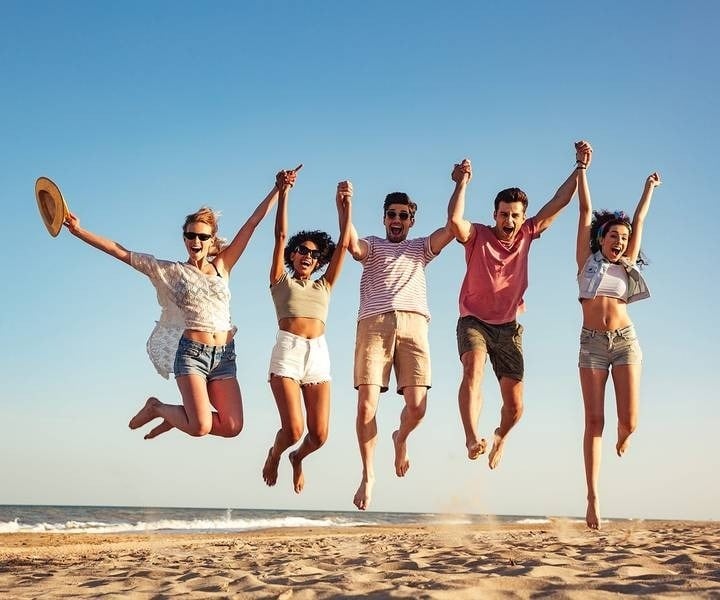 Group of friends holding hands, jumping on the beach of the Hotel Park Royal Beach Huatulco