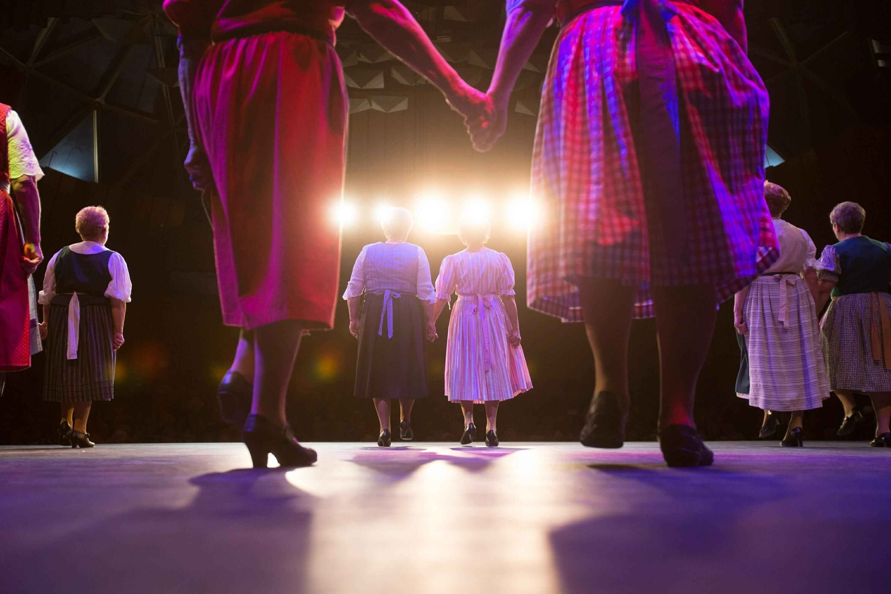 um grupo de pessoas está dançando em um palco segurando as mãos