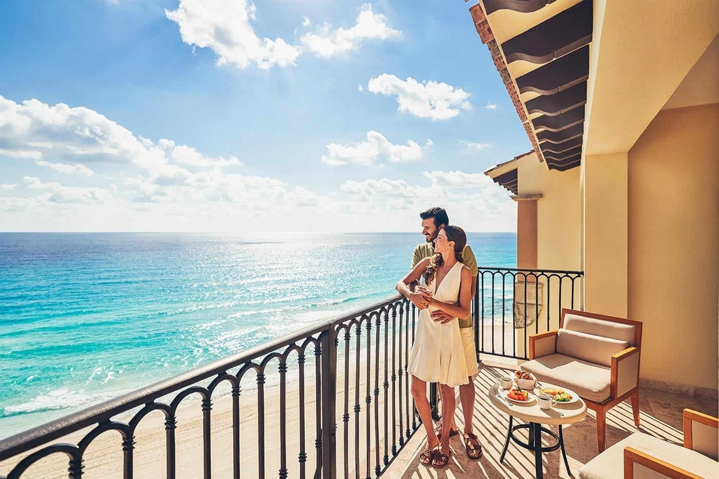 Couple on balcony at Hotel Grand Park Royal Cancun, overlooking Mexican Caribbean beach.