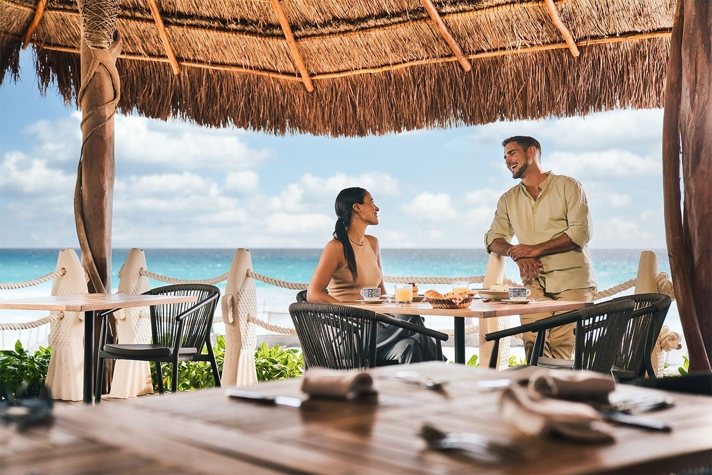 Pareja disfrutando desayuno frente al mar en Royal Select at Grand Park Royal Cancún. Reserva tu estancia.