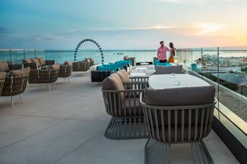 Pareja disfrutando en la terraza de un bar del Hotel Park Royal Beach Cancún con vistas al mar y cerca de una noria 
