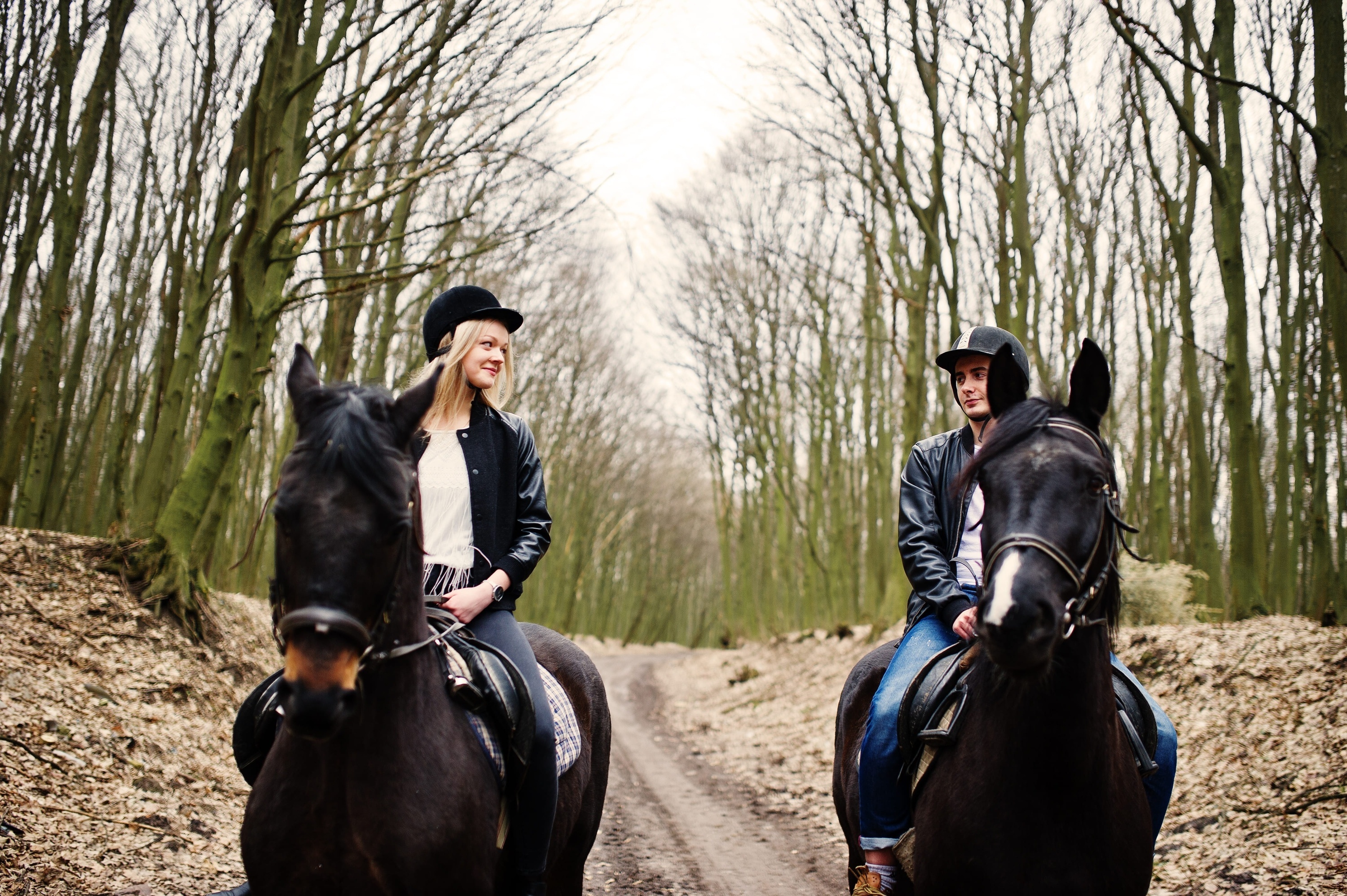 um homem e uma mulher andam a cavalo em uma estrada de terra