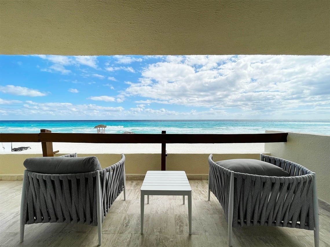 Room terrace with tables and chairs and ocean view at The Villas by Grand Park Royal Cancún