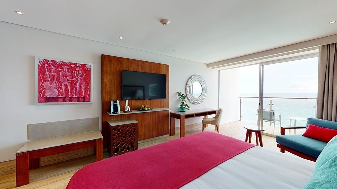 Grande quarto com banco, TV e varanda do Hotel Grand Park Royal Puerto Vallarta