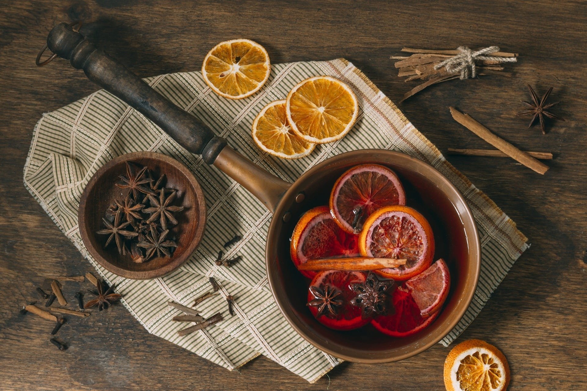 uma panela cheia de laranjas e especiarias em uma mesa de madeira