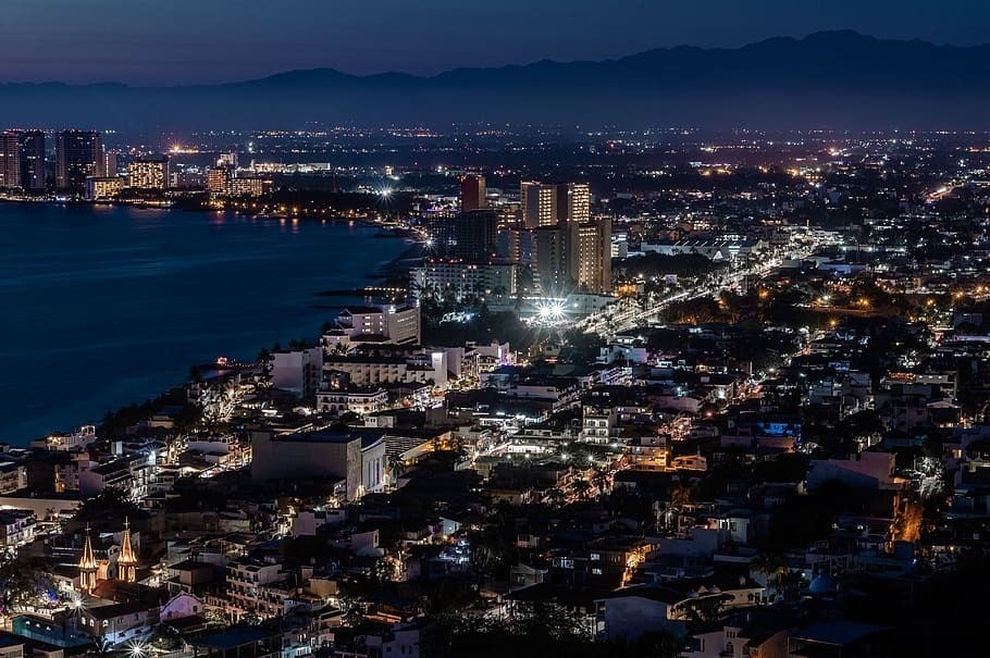 una vista aérea de una ciudad por la noche con el océano al fondo