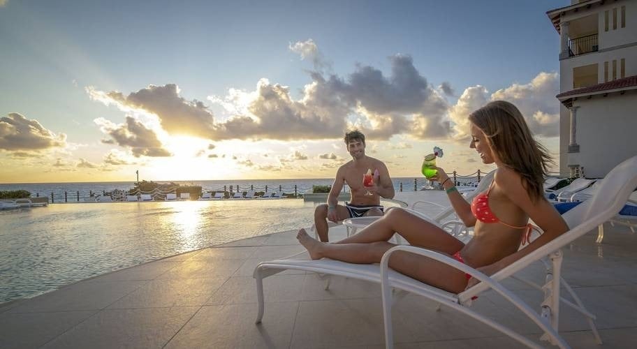 Pareja bebiendo un cóctel en una piscina con vistas al mar Caribe en el Hotel Grand Park Royal Cancún
