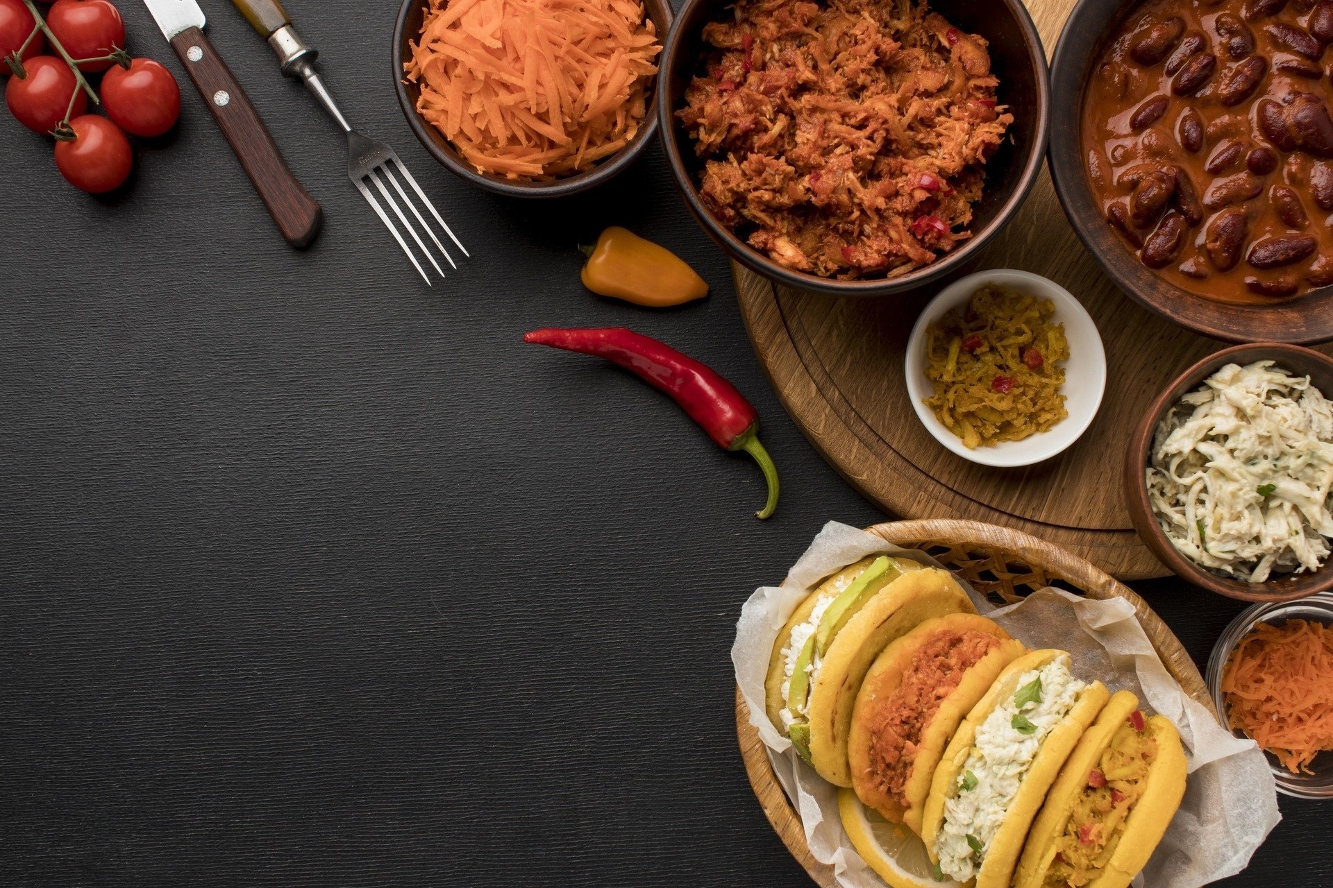 una tabla de cortar de madera rodeada de platos de comida y utensilios de cocina