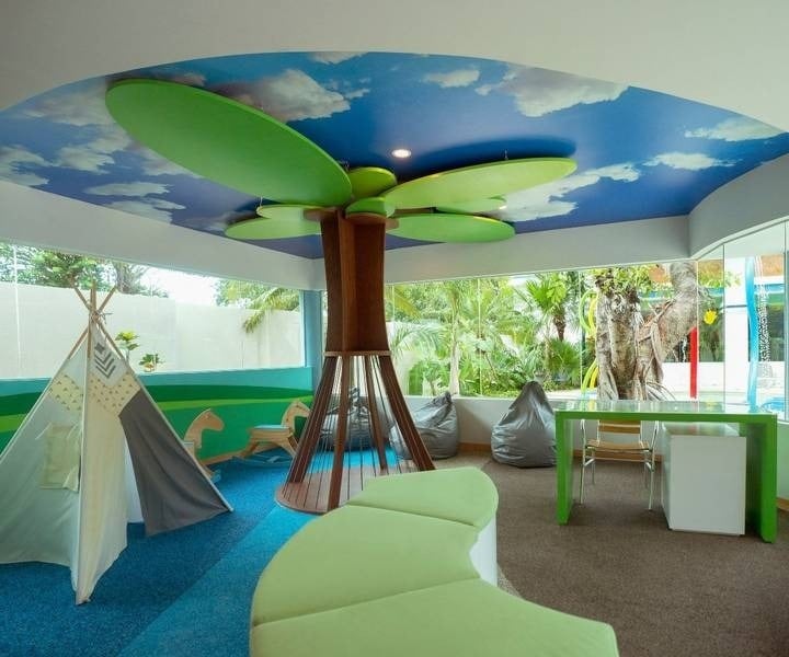 Área infantil con árbol como columna, tiendas de indios y puffs del Hotel Grand Park Royal Cozumel