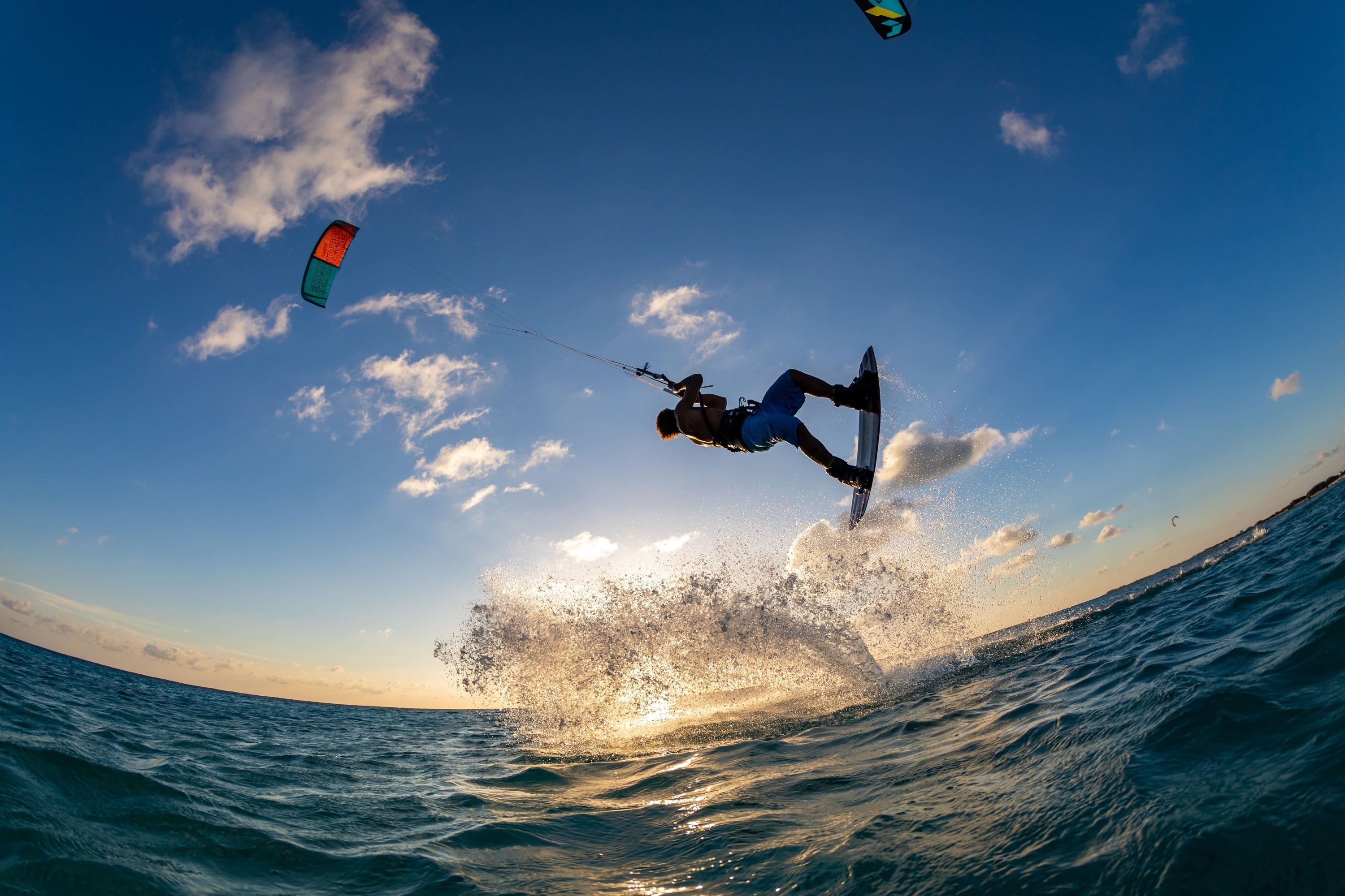 un hombre salta en el aire mientras hace kitesurf
