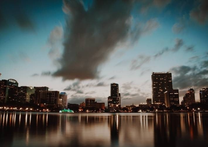 o horizonte da cidade está refletido na água ao pôr do sol .