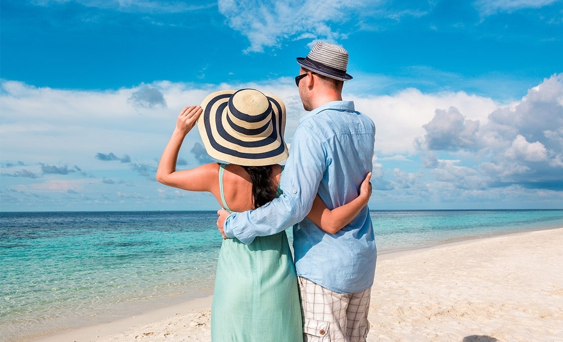 um homem e uma mulher estão de pé na praia olhando para o oceano