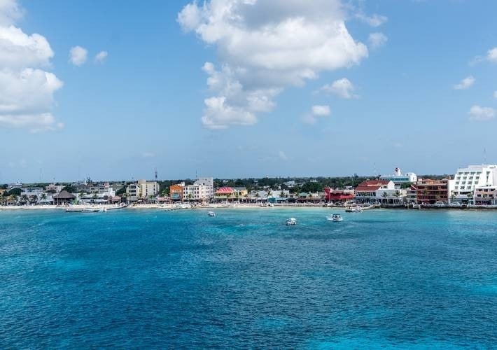 um grupo de barcos está flutuando no oceano em frente a uma cidade .