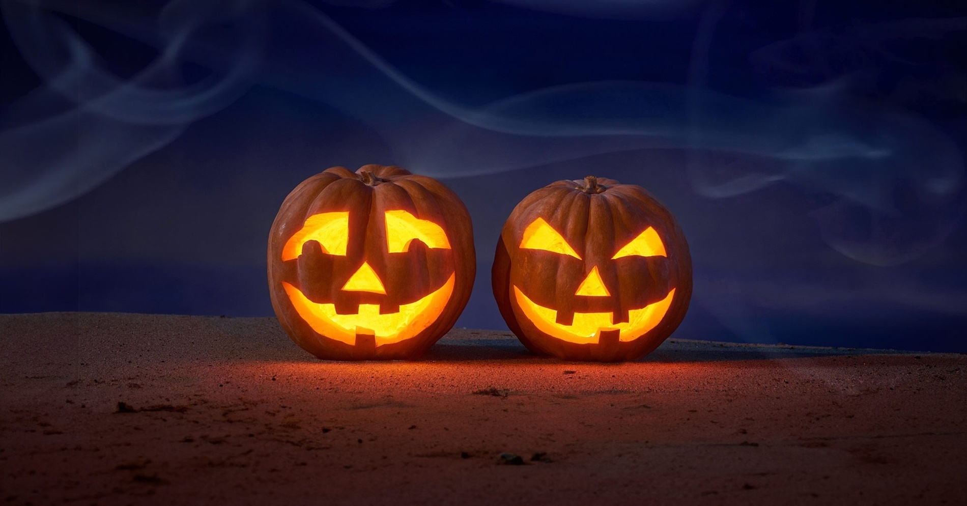 two carved pumpkins are lit up in the dark