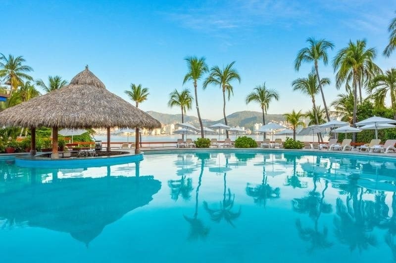 Bar con tejado de palma, junto a piscina exterior y vistas al mar del Hotel Park Royal Beach Acapulco