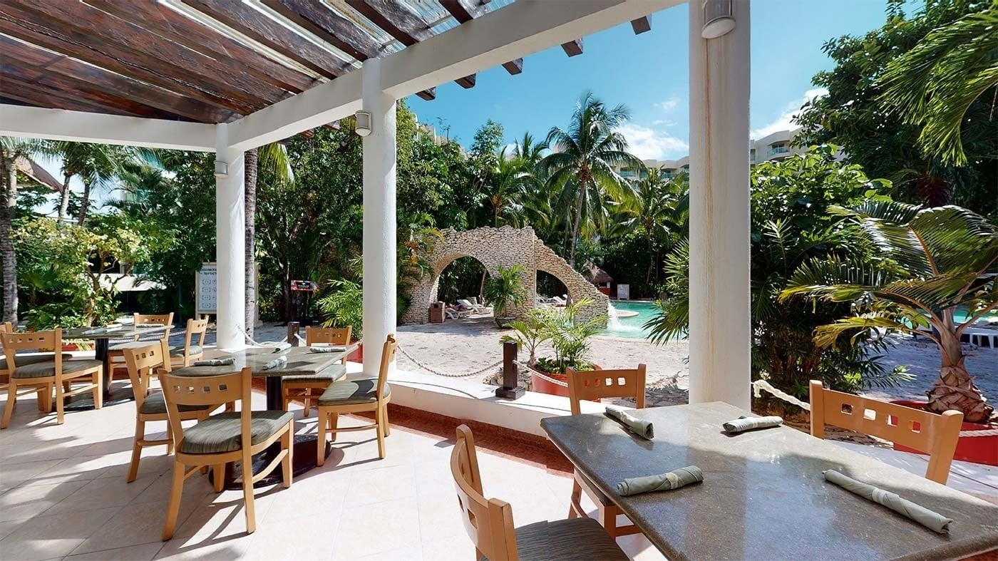 Park Royal: Corpo. Mesas exteriores bajo pérgola con vista a piscina y vegetación tropical.