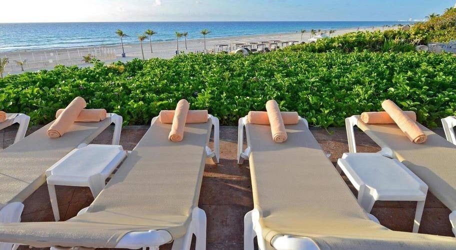 Hamacas de piscina con toallas enrolladas cerca de la playa en el Hotel Park Royal Beach Cancún