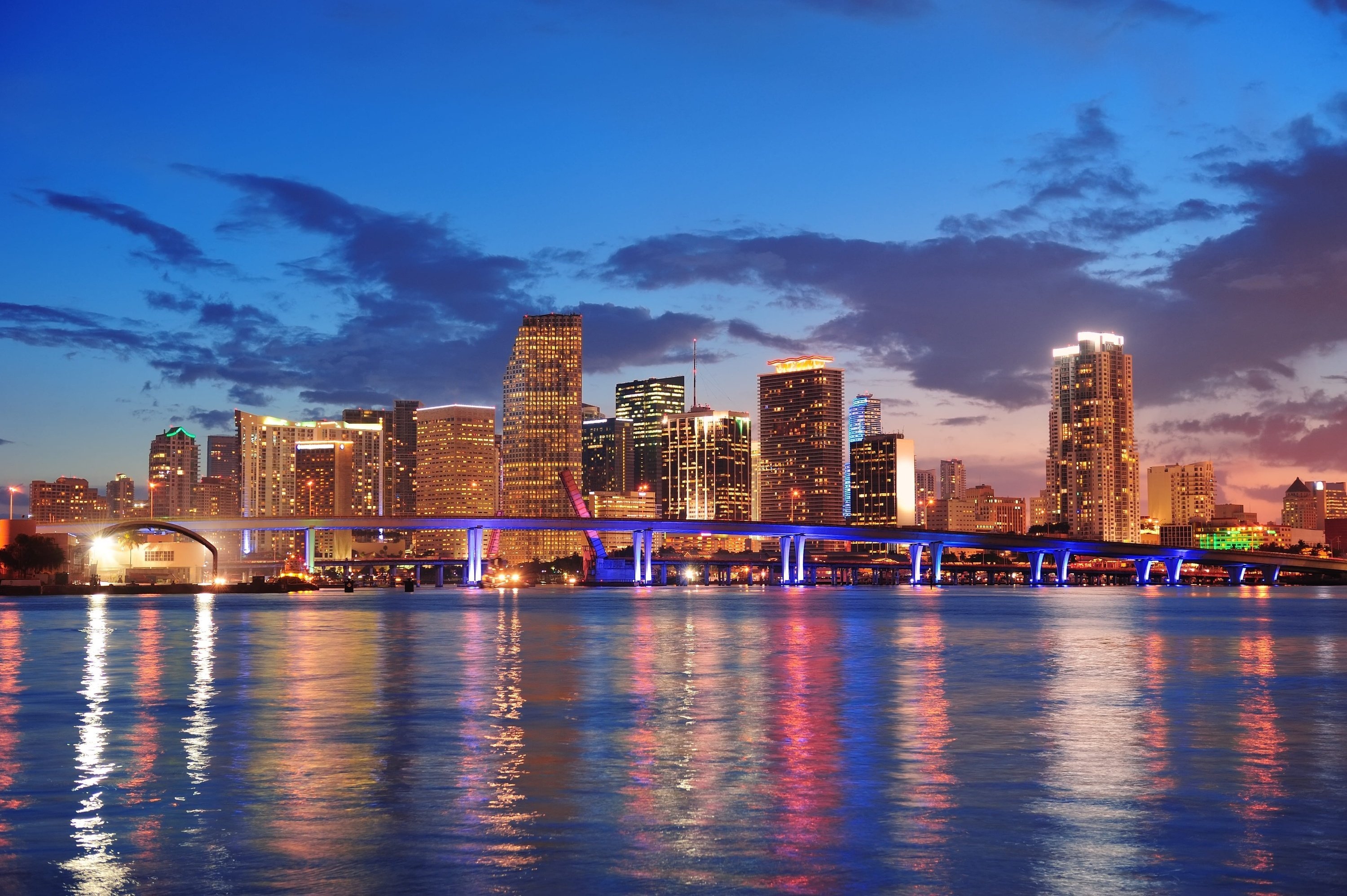 a city skyline at night with a bridge in the foreground