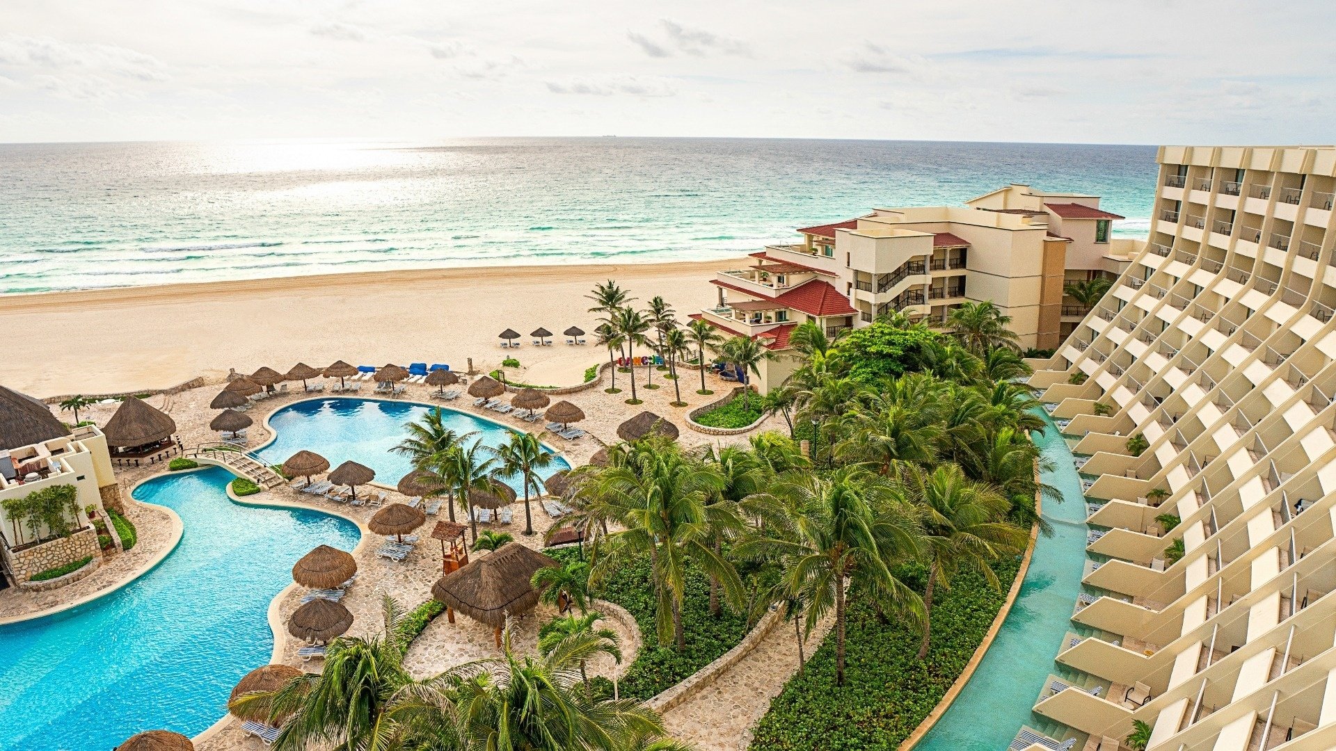 una gran piscina rodeada de palmeras y una playa