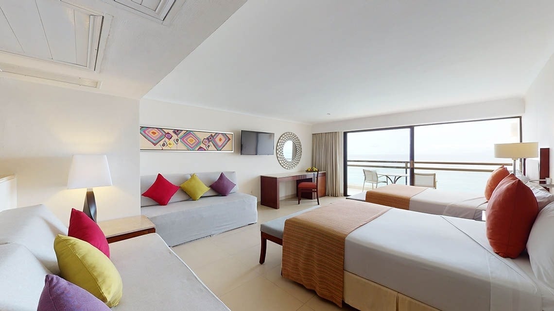 Quarto espaçoso com sofás, camas e varanda com vista para o mar no Hotel Grand Park Royal Puerto Vallarta