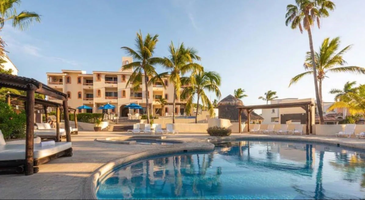 a large swimming pool in front of a hotel with palm trees