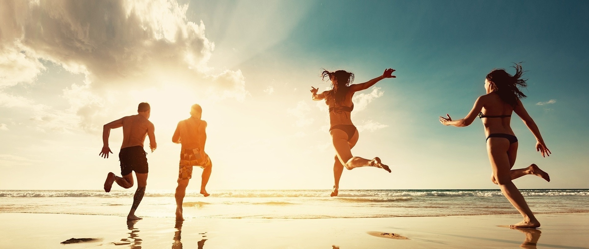 um grupo de pessoas correndo na praia ao pôr do sol