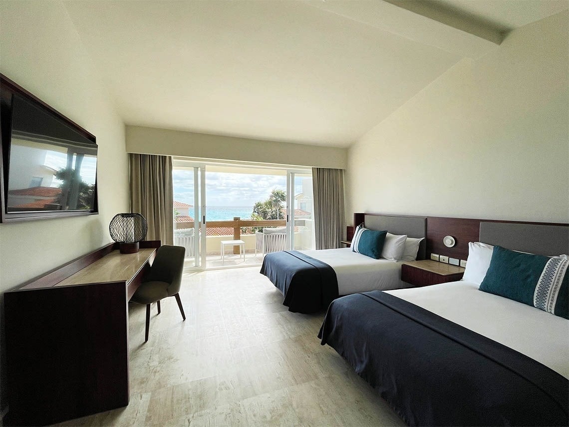 Dormitorio con camas dobles y vistas al mar de The Villas by Grand Park Royal Cancún 