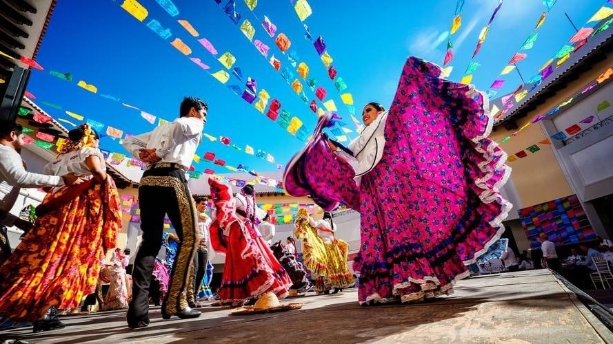 a group of people in traditional mexican costumes are dancing on a stage