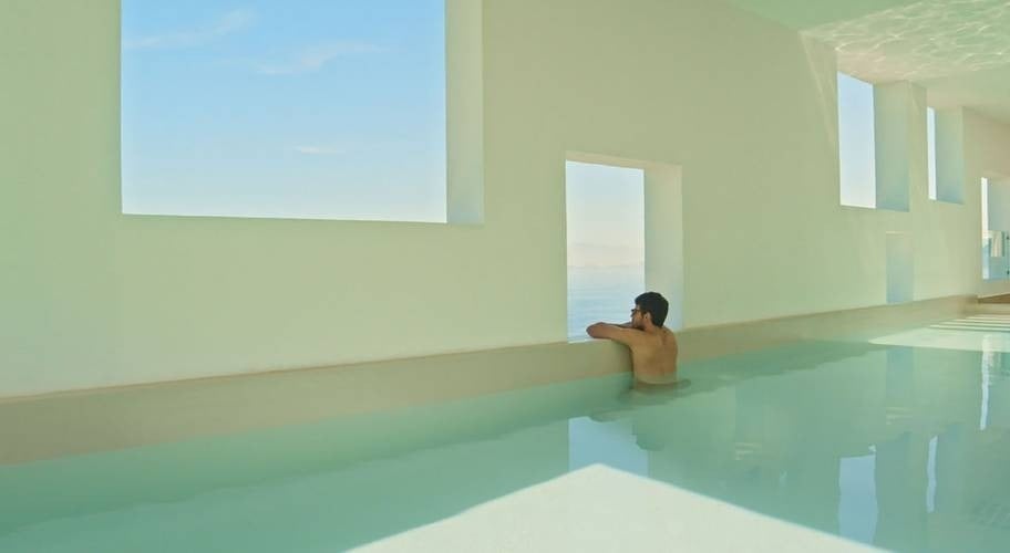 Homem olhando pela janela na piscina coberta Ekinox no Park Royal Grand Puerto Vallarta