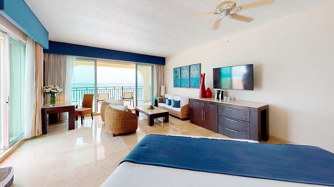 Habitación con cama king size, área de descanso y terraza con vista al mar Caribe del Hotel Grand Park Royal Cancún