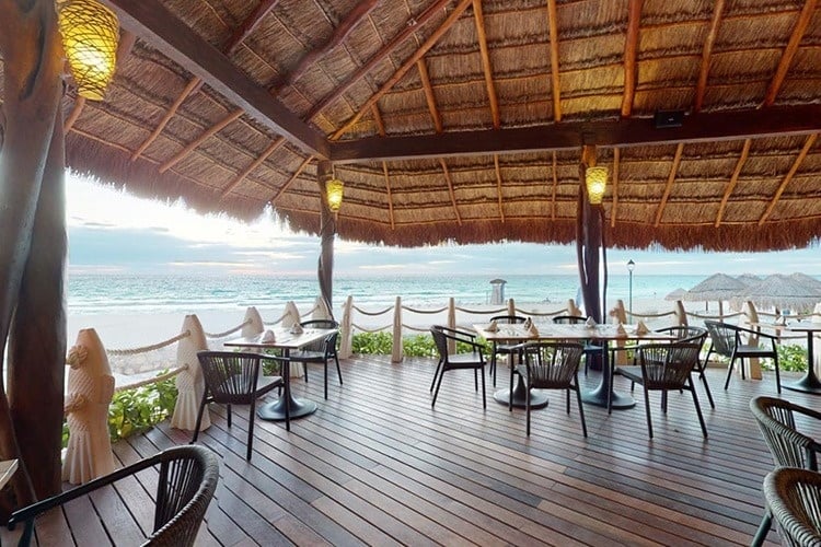 un restaurante en la playa con mesas y sillas