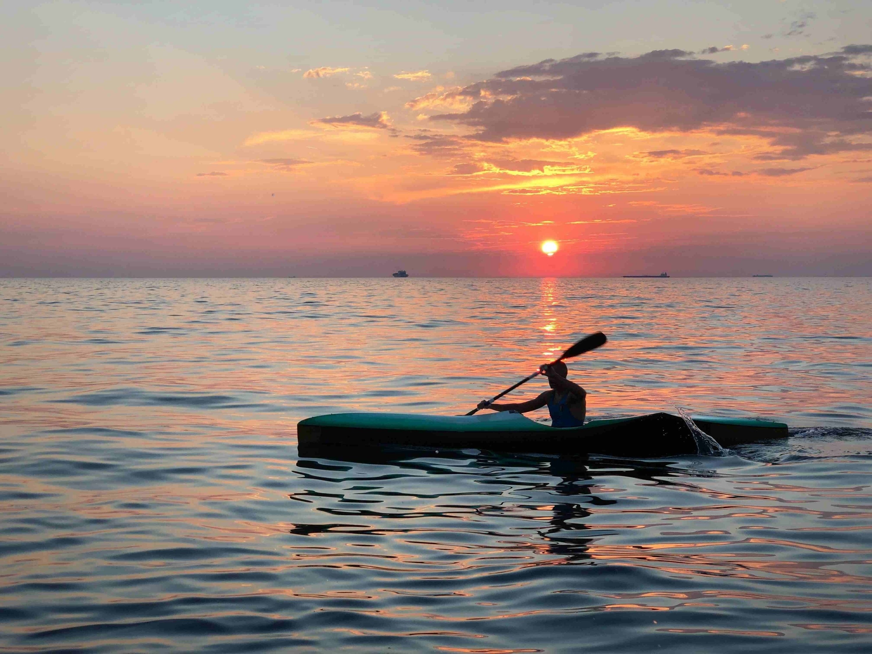 a person is paddling a kayak in the ocean at sunset