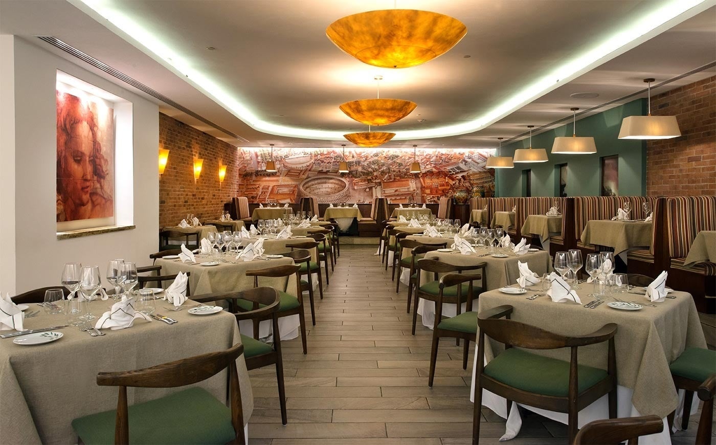 Elegante salón comedor del Hotel Park Royal Beach Cancún con mesas puestas y arte mural.