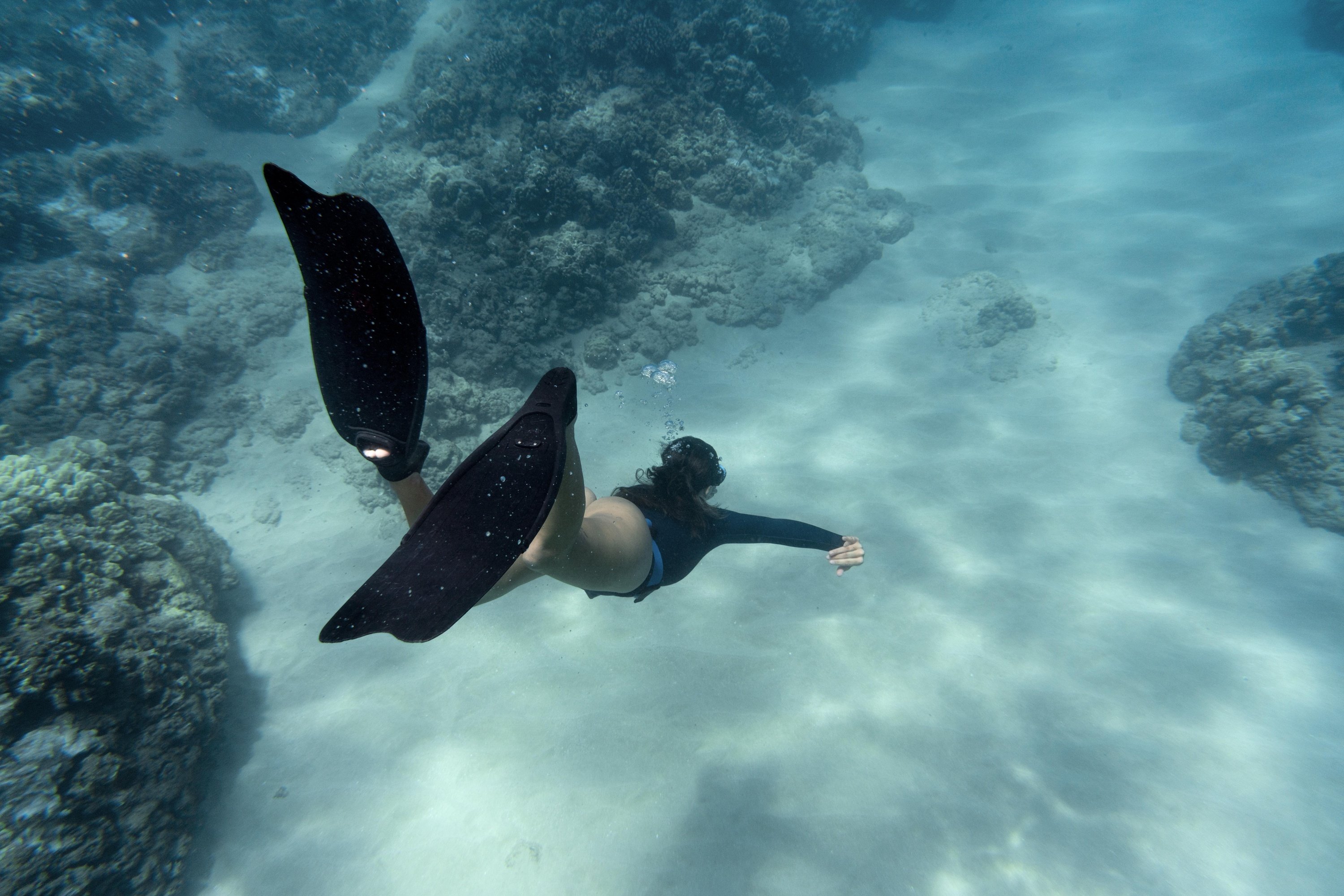 a woman is swimming in the ocean with black fins