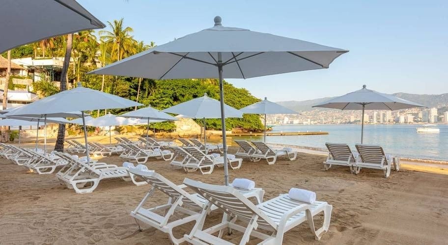 Redes e guarda-chuvas brancos na praia do Hotel Park Royal Beach Acapulco