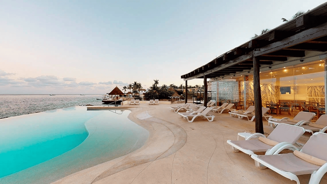 un patio con sillas y una piscina infinita con vistas al océano