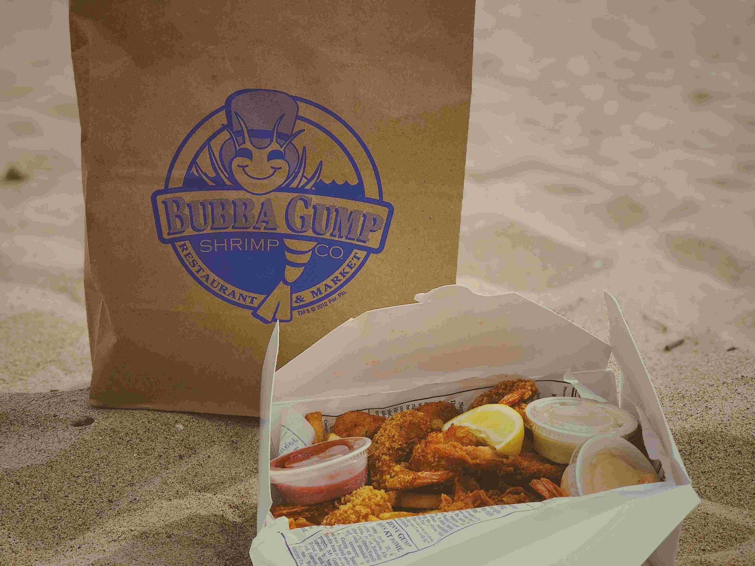 uma caixa de camarão frito ao lado de uma sacola de bubba gump