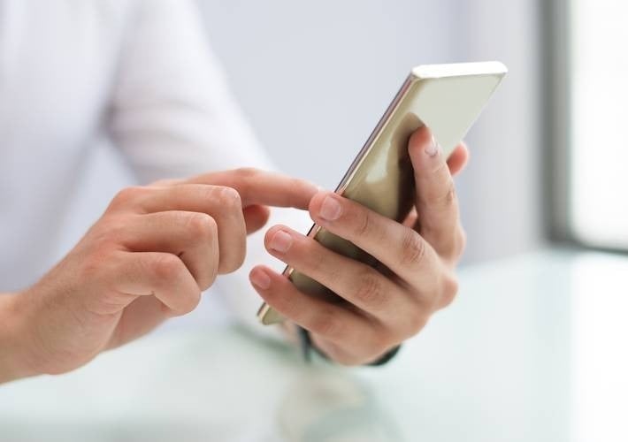 a man is using a smart phone while sitting at a table .