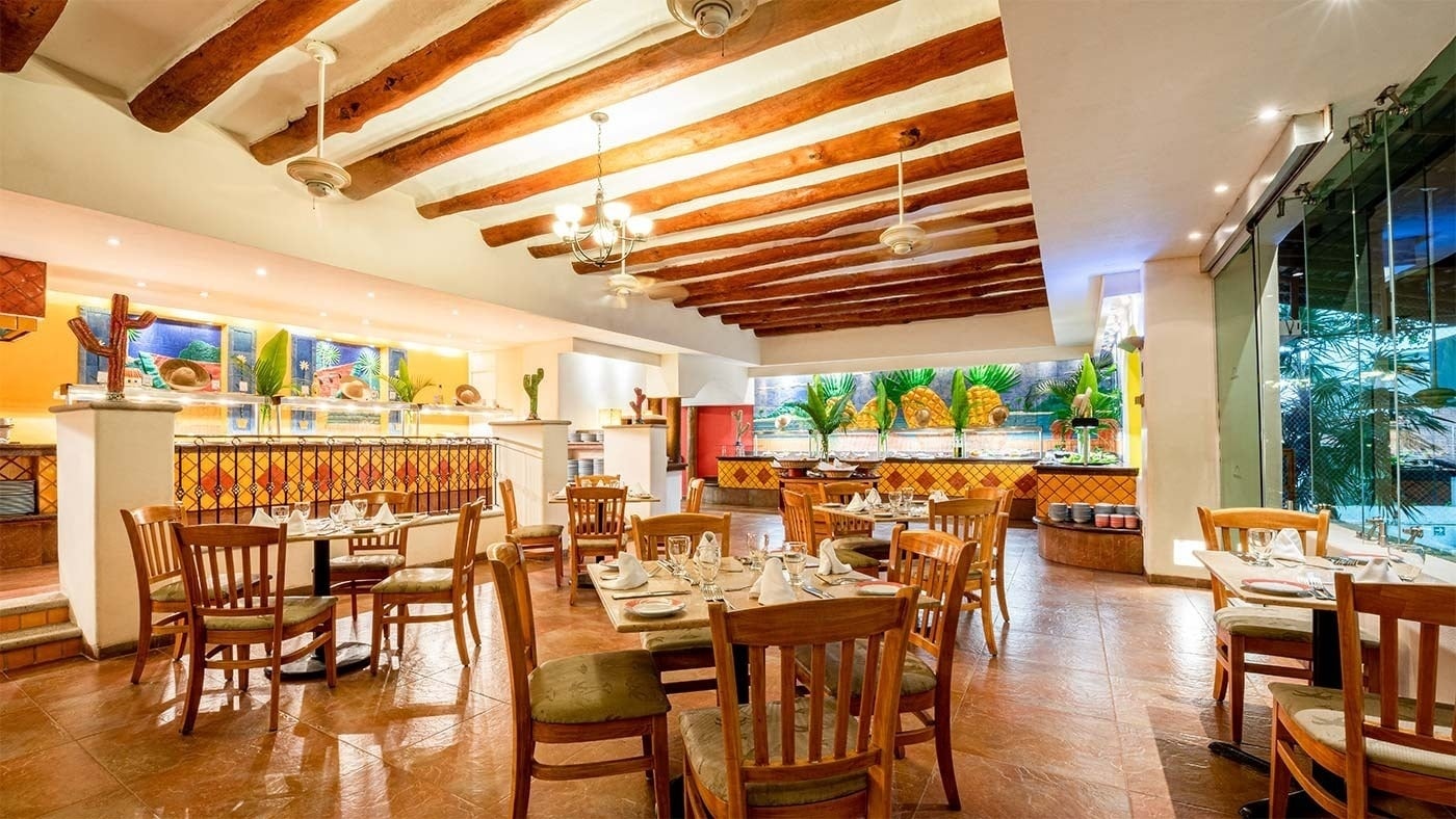 Comedor del Hotel Park Royal Beach Ixtapa, con mesas de madera y vista a la piscina.