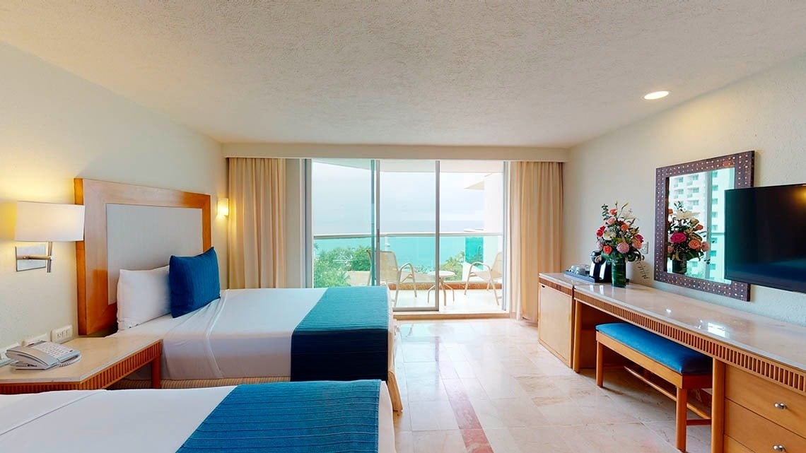 Dormitorio con dos camas y balcón con vistas al mar del Hotel Grand Park Royal Cozumel