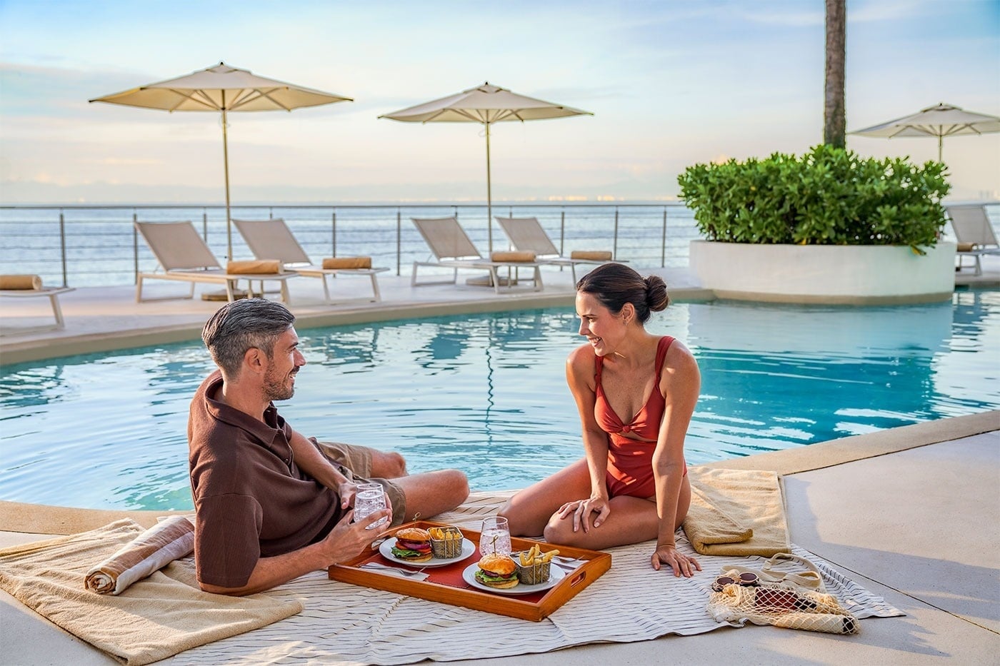 Pareja disfrutando de un picnic junto a la alberca en Hotel Grand Park Royal Puerto Vallarta | Pacífico Mexicano.